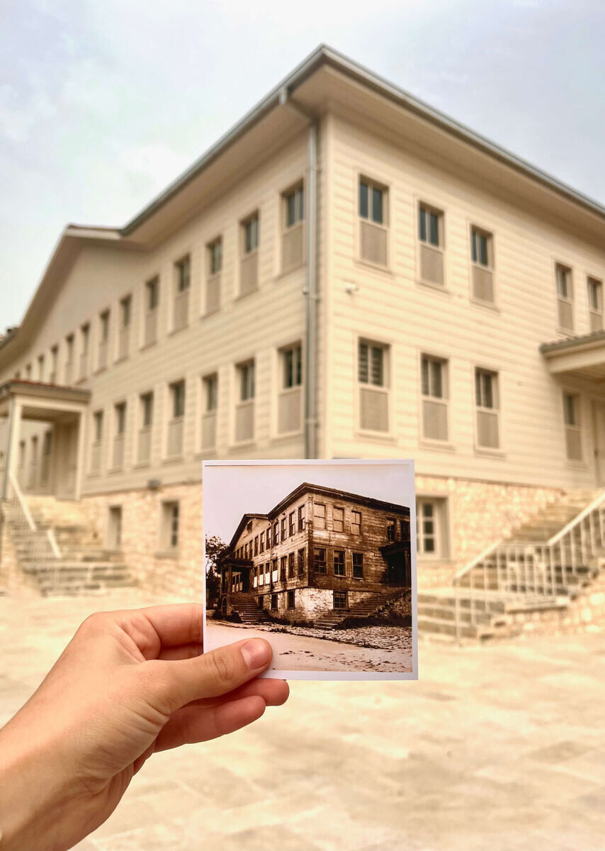 A hand holding an old photograph of the original Kasımpaşa Mevlevihanesi in front of the rebuilt lodge