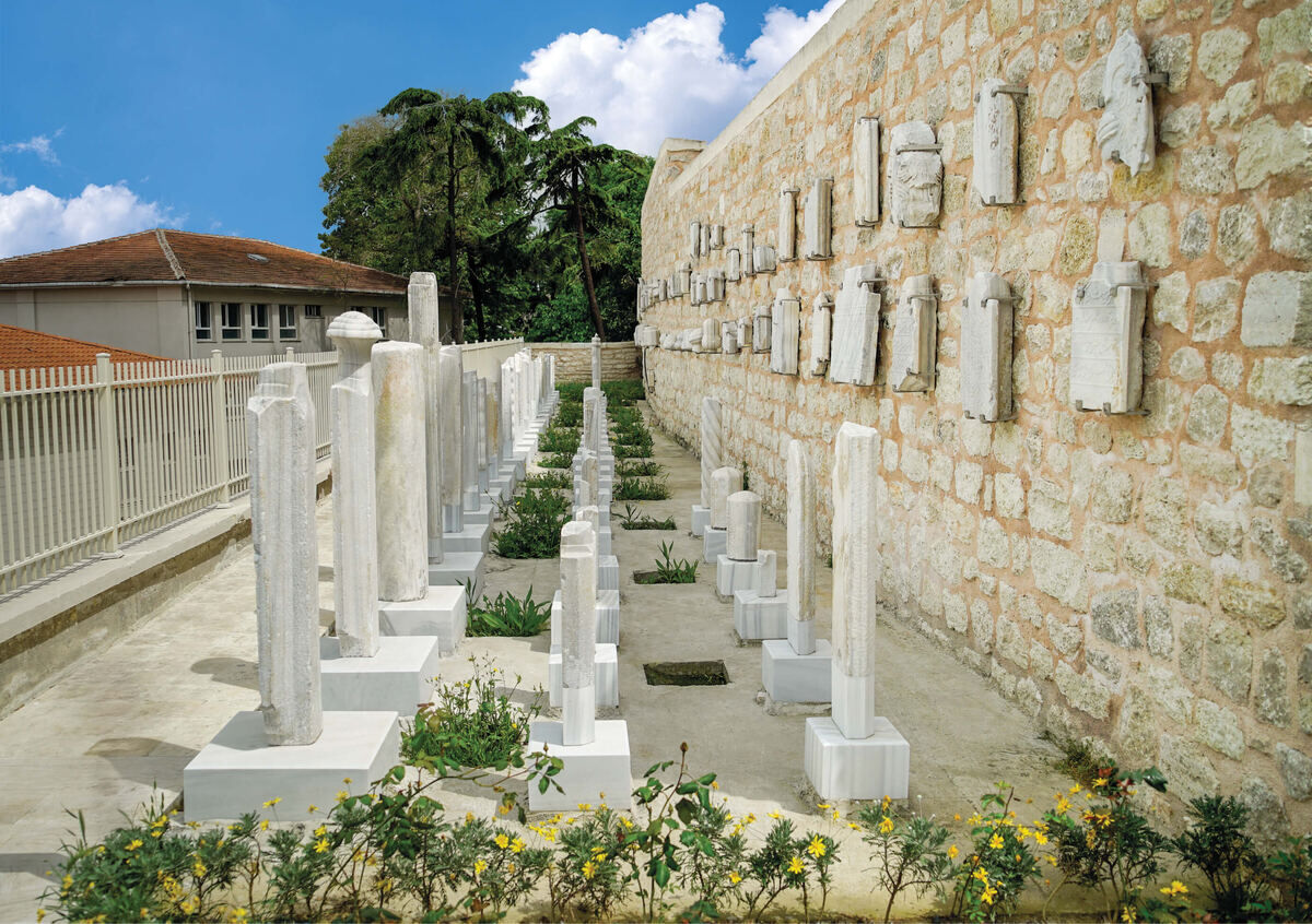 Rows of tall Ottoman headstones and fragments set into a stone wall in the graveyard of Kasımpaşa Mevlevihanesi