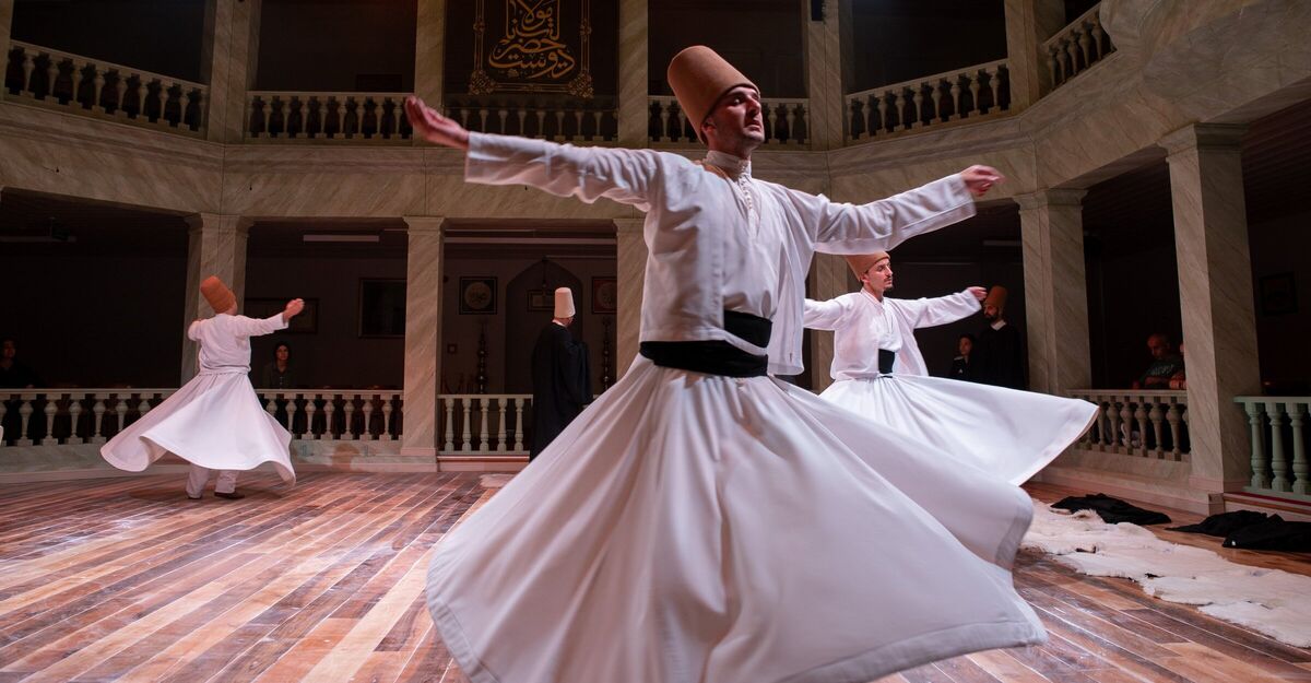 A whirling dervish with arms open wide, right palm turned up and left palm down, in the Kasımpaşa ceremony hall