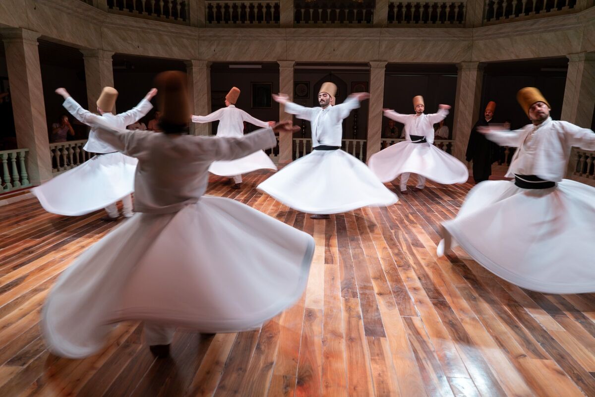 Five whirling dervishes turning with arms raised during the Sema at Kasımpaşa Mevlevihanesi, Istanbul